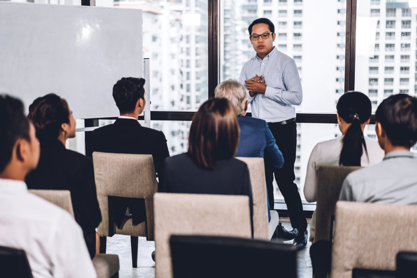 Businessman standing in front of group of people in consulting meeting conference seminar at hall or seminar room presentation and coaching concept